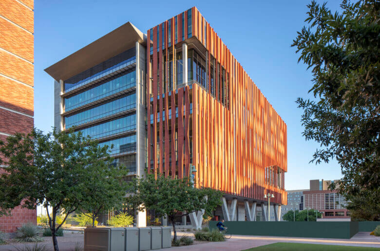 A modern building on a campus with a large wall of windows and rust colored accents created by the architectural design team at Swaim Associates