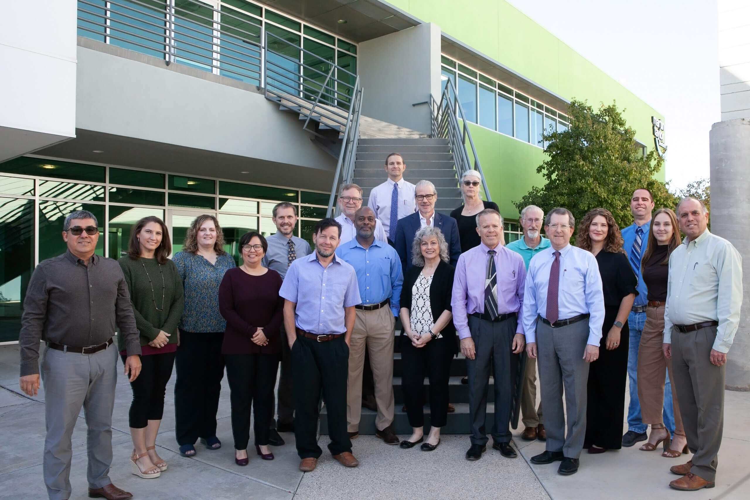 A large team of architects that specialize in architectural design standing in front of the Swaim Associates office